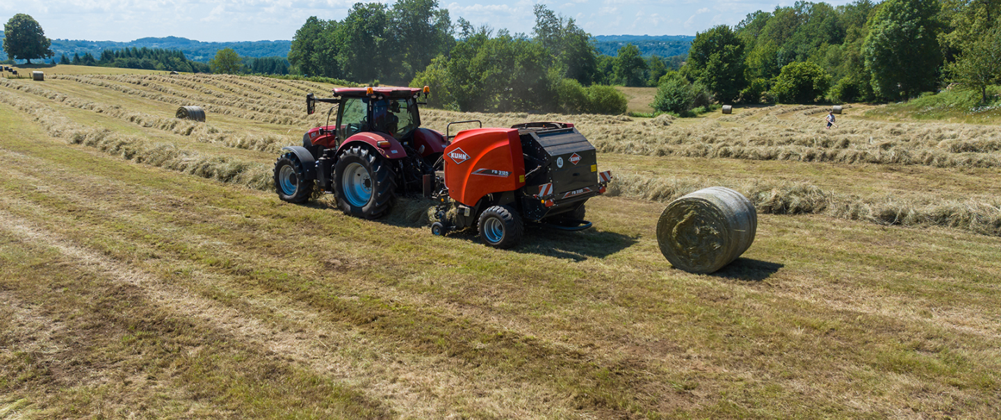 KUHN FB 3125 fixed round baler is baling round bales of silage