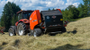 KUHN FB 3125 fixed round baler with the operator in the field in the background